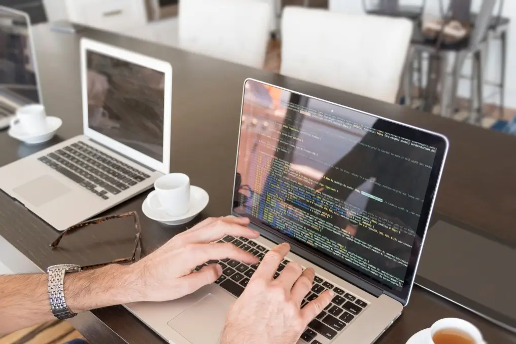Man writing software code on laptop