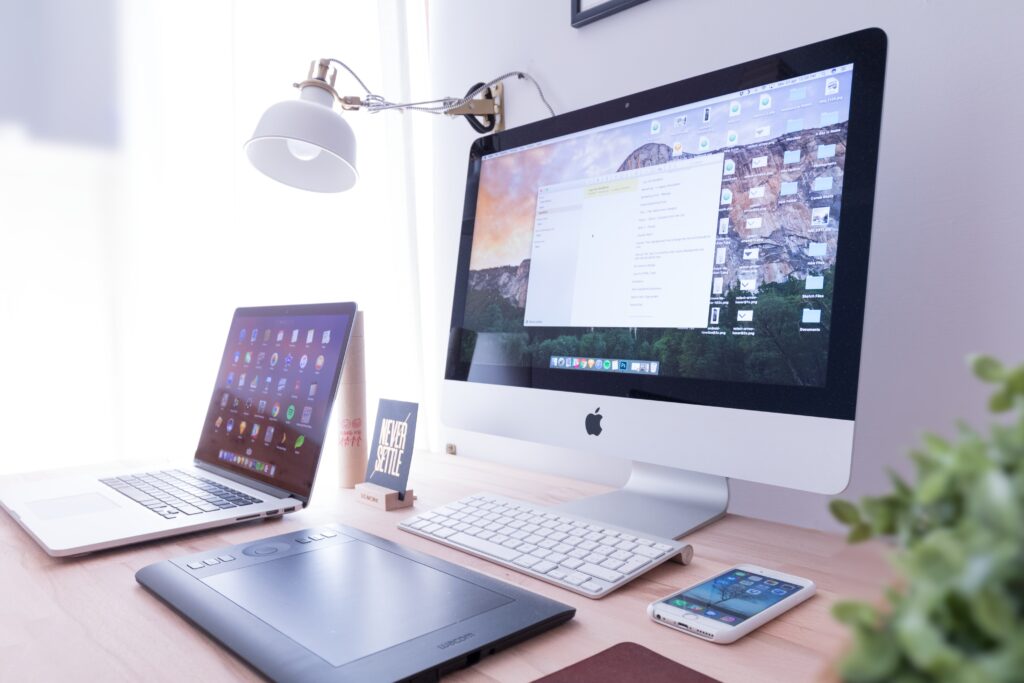 A computer, laptop and cellphone on a table